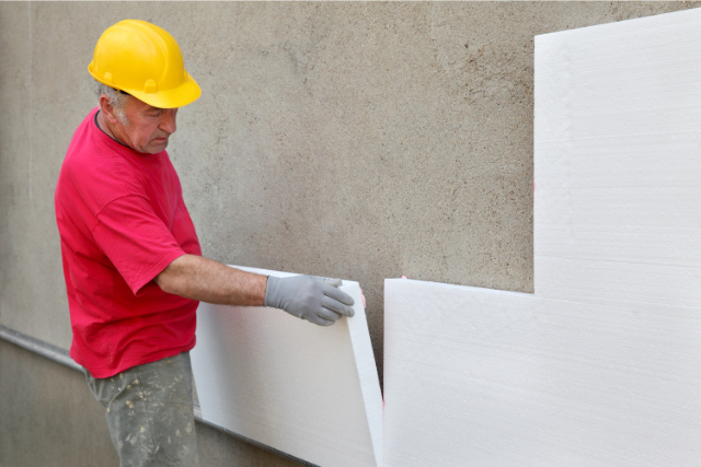 Thermal Wall insulation by worker with a yellow hard hat on.